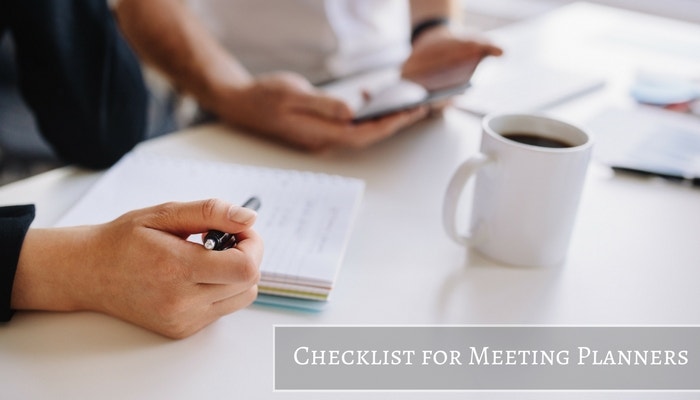 Close up of two meeting planners working on a checklist with a cup of coffee